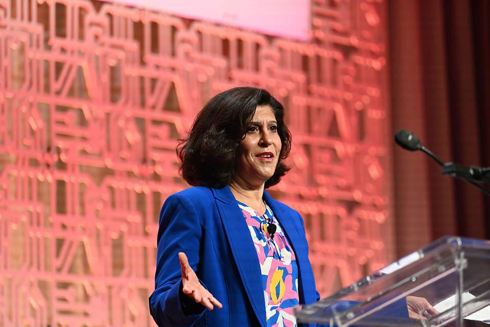 Alameh speaks at a podium during a conference.