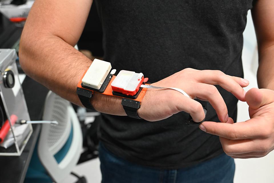 A prototype of a haptic device sits on the wrist of a researcher.